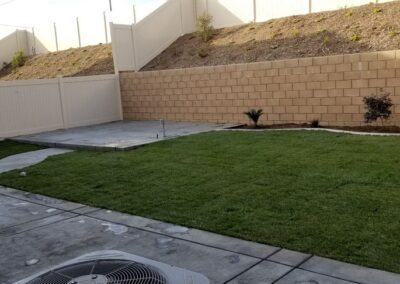 A small backyard with grass and a wall.