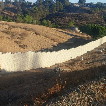 A white wall is being built on a hillside.