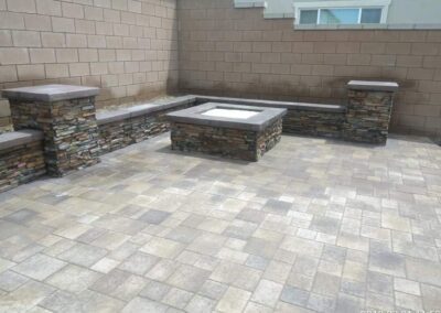 A stone patio with a fire pit in the middle.